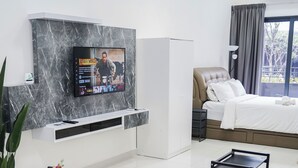 A modern hotel room with a marble wall, a flat-screen TV, a bed with a headboard, a dining table with chairs, and a small side table. - KLIA AIRPORT HOMESTAY 5 (Sepang)