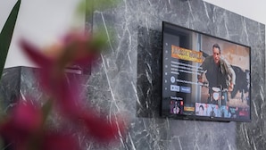 A flat-screen TV mounted on a wall with a marble-like texture. - KLIA AIRPORT HOMESTAY 5 (Sepang)