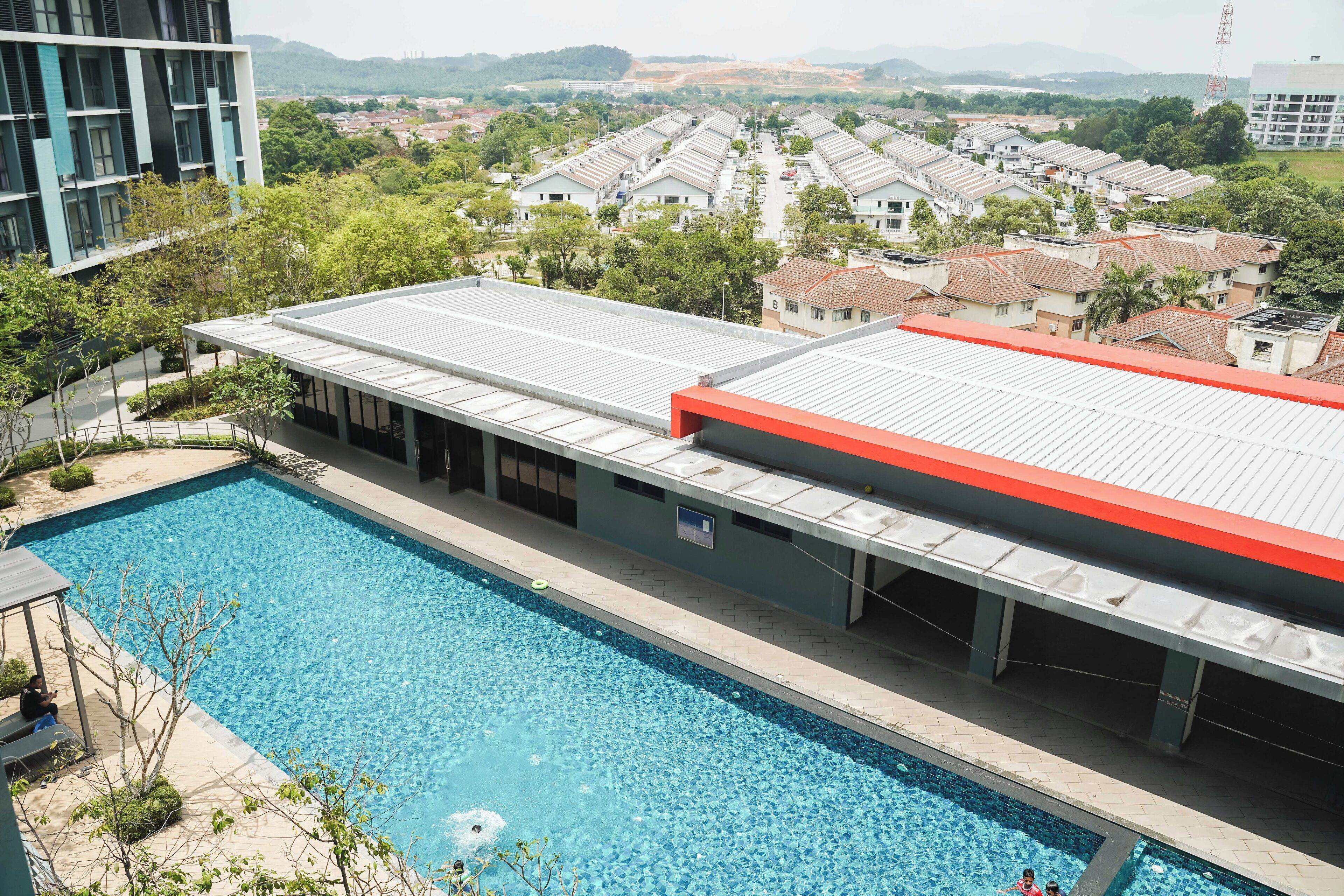 A swimming pool with a covered area, surrounded by residential buildings and greenery.