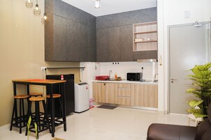 A compact kitchen with a dining area, a refrigerator, a microwave, and a sink.