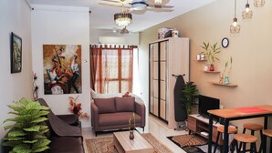 A living room with a sofa, coffee table, TV, and a dining area with stools. - KLIA AIRPORT HOMESTAY 8 (Sepang)