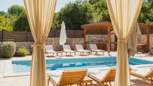 A poolside area with lounge chairs and a pergola. - Lulu in Dobrinj With 4 Bedrooms and 4 Bathrooms (Dobrinj)