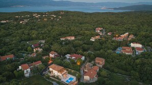An aerial view of a residential area with houses surrounded by greenery, a swimming pool, and a view of the sea. - Lulu in Dobrinj With 4 Bedrooms and 4 Bathrooms (Dobrinj)