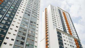 Zwei hohe Wohngebäude mit mehreren Stockwerken und Balkonen, die ein modernes architektonisches Design aufweisen.