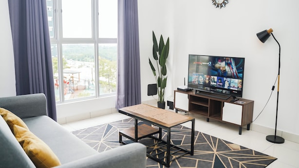 Ein modernes Wohnzimmer mit einer Couch, einem Couchtisch, einem Fernseher und einer Pflanze.