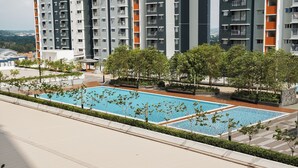 Ein moderner Apartmentkomplex mit mehreren Hochhäusern, einem zentral gelegenen Pool und gepflegter Bepflanzung.