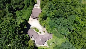 Vue aérienne d’une propriété résidentielle avec une grande maison, entourée d’une végétation luxuriante.