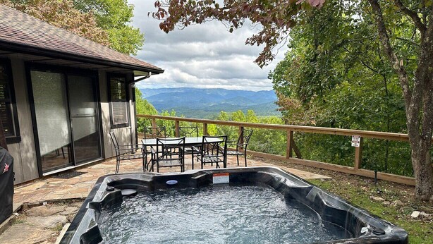 Un bain à remous avec vue sur les montagnes, entouré d’une terrasse en bois et de mobilier d’extérieur.