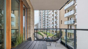 Un balcón con una mesa de madera y dos sillas, con vista a un edificio de gran altura con varios balcones.