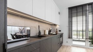 Una cocina moderna con una isla grande, electrodomésticos integrados y un ventanal con persianas.
