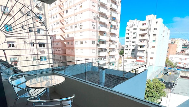 A balcony with a table and chairs, overlooking a cityscape with multiple buildings. - Brand new studio in Almagro with rooftop terrace, bathtub and balcony | Hospital Italiano, audiovisual hub & Av. Corrientes (Buenos Aires)