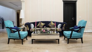 A room with a dark blue sofa set, two matching armchairs, a wooden coffee table, and a decorative centerpiece. - Grace Guest House (Islamabad)