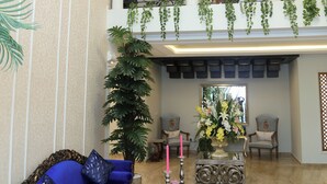 A spacious lobby with a blue sofa, a glass coffee table, and a chandelier. - Grace Guest House (Islamabad)
