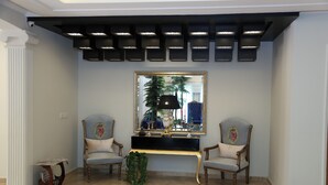 A room with a large mirror, two armchairs, a console table, and a decorative plant. - Grace Guest House (Islamabad)