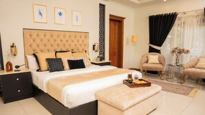 A spacious bedroom with a large bed, two bedside tables, a nightstand, a sofa, and a small round table. - Grace Guest House (Islamabad)