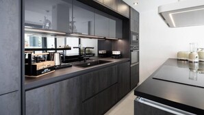 Une cuisine moderne avec des meubles de couleur sombre, un évier en acier inoxydable et une hotte aspirante.