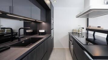 A modern kitchen with dark cabinetry, stainless steel appliances, and a sleek countertop design.