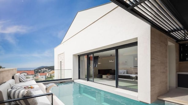 Une maison moderne dotée d’une piscine, de grandes baies vitrées et offrant une vue sur la mer.