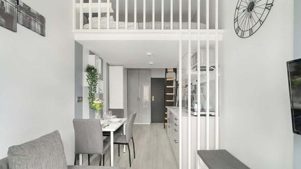 A modern apartment with a dining area, a living room with a sofa, a balcony, and a kitchen.