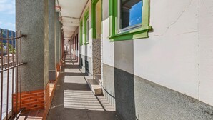 A corridor with a tiled floor, green-framed windows, and a brick wall on one side. - 1 bedroom nice apartment in Kaub (Kaub)
