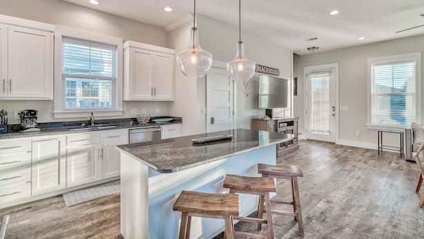 A spacious kitchen with white cabinets, a large island with stools, and pendant lighting. - Newly-Renovated Beach Home with Private Pool Quick Beach Access! Slps 16 (Panama City Beach)