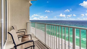 Ein Balkon mit Blick auf das Meer, ausgestattet mit Geländer und einer Sitzgruppe mit Stühlen und einem Tisch.