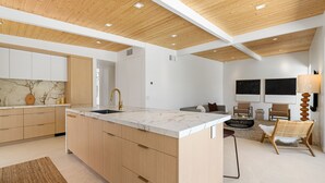 A modern kitchen with wooden cabinets, a marble countertop, and a large island. - Desert Willow-Iconic Butterfly Alexander (Palm Springs)