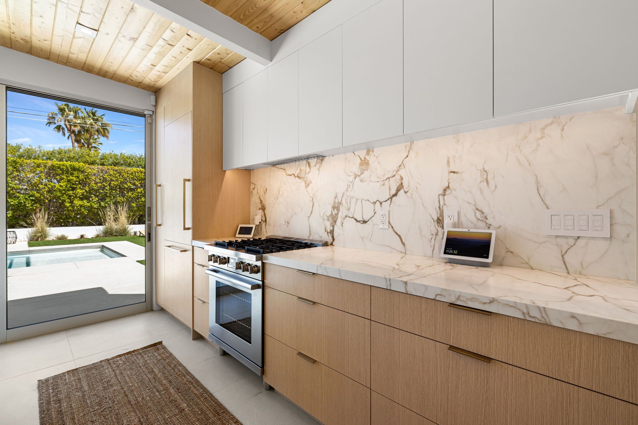 A modern kitchen with a marble backsplash, built-in oven, and a tablet on the countertop.