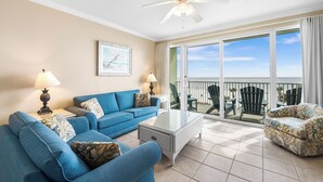 Ein Wohnzimmer mit einem blauen Sofa, einem Glastisch und einem Deckenventilator.