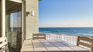 A balcony with a table and chairs overlooking the ocean. - Deluxe Beachfront Condo (Panama City Beach)
