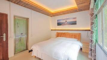 A bedroom with a wooden ceiling, a bed with white bedding, a painting of a pier, and a window with curtains.