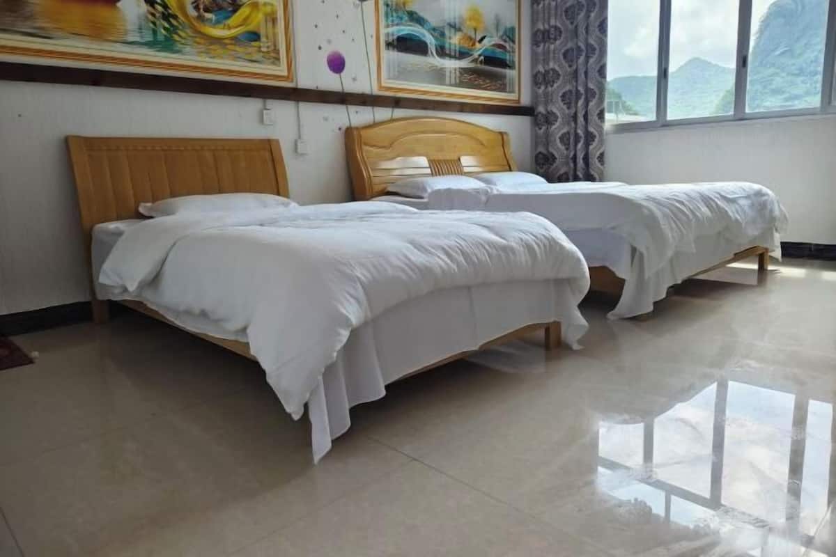 Habitación de hotel con dos camas de madera, ropa de cama blanca y un ventanal con vistas a las montañas.