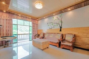 Relax in this spacious room with a high ceiling, featuring a sofa set and a wall-mounted artwork.