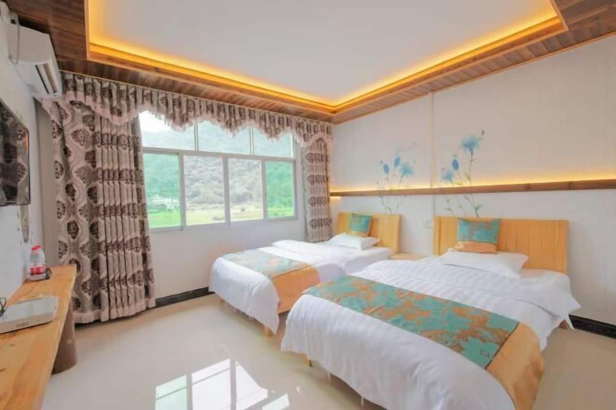 Habitación de hotel con dos camas, un escritorio y una ventana con cortinas.
