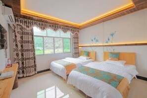 Habitación de hotel con dos camas, un escritorio y una ventana con cortinas.