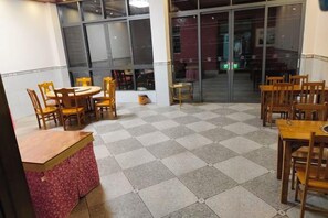 A dining area with tables and chairs, a counter, and a glass door leading outside. - Libomaolan Shengyuan Nongjiale (Libo)