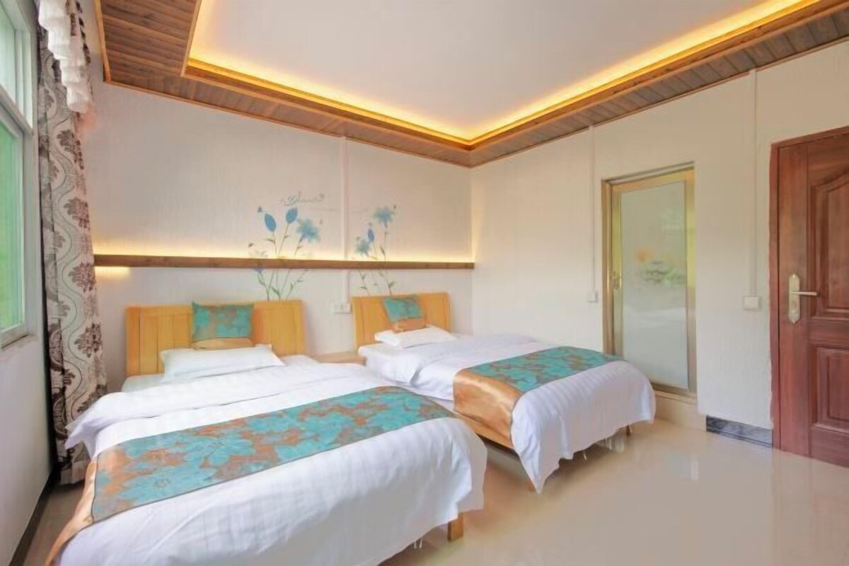 A hotel room with two beds, a wooden ceiling, and a door.