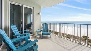Un balcon avec deux fauteuils Adirondack, une petite table et une vue sur la plage.
