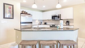 Eine moderne Küche mit weißen Schränken, einer Granit Arbeitsplatte, Edelstahlgeräten und einer Kaffeemaschine.