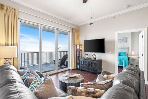A living room with a view to the balcony, a flat-screen TV, and a cozy seating area. - Newly Renovated Upscale Beachfront Condo (Panama City Beach)