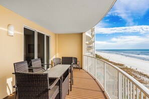 A balcony with wicker furniture, a view of the beach, and a white railing. - Big Beachfront Balcony for Parties of 7 with a set of beach chairs included! (Panama City Beach)