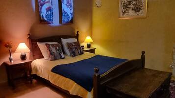 A bedroom with a wooden bed, two bedside lamps, a rug, and a painting on the wall.