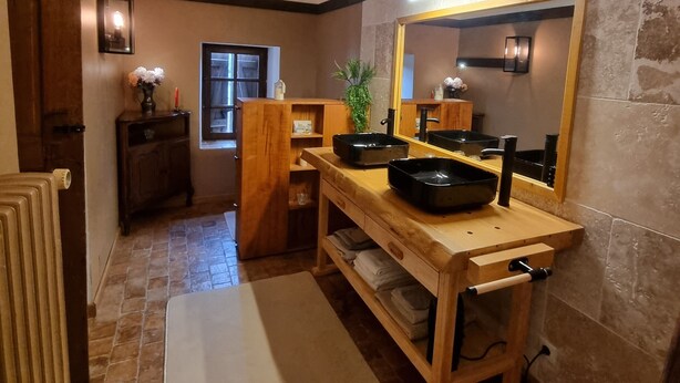 Maalaishenkinen keittiö, jossa on puupalkit, kiviseinä ja suuri peili.