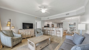 Un salon comprenant un canapé, des fauteuils, une table basse, un téléviseur et un ventilateur de plafond.