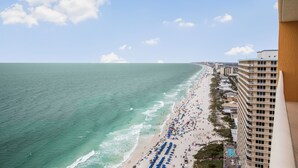 Un hôtel situé sur la côte, offrant une vue sur la plage, doté de plusieurs balcons et d’un espace piscine.