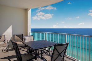 A balcony with a table and chairs, overlooking a clear blue sea. - Unwind in This Tropical Oasis! (Panama City Beach)