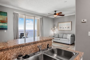A kitchen with granite countertops, stainless steel sink, and a ceiling fan. - Unwind in This Tropical Oasis! (Panama City Beach)