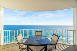 Ein Balkon mit Tisch und Stühlen, mit Blick auf ein Gewässer.