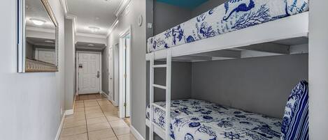 Un couloir avec des lits superposés, une porte et un miroir.