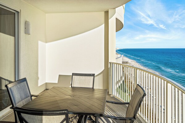 Ein Balkon mit Tisch und Stühlen, mit Blick auf Strand und Meer.